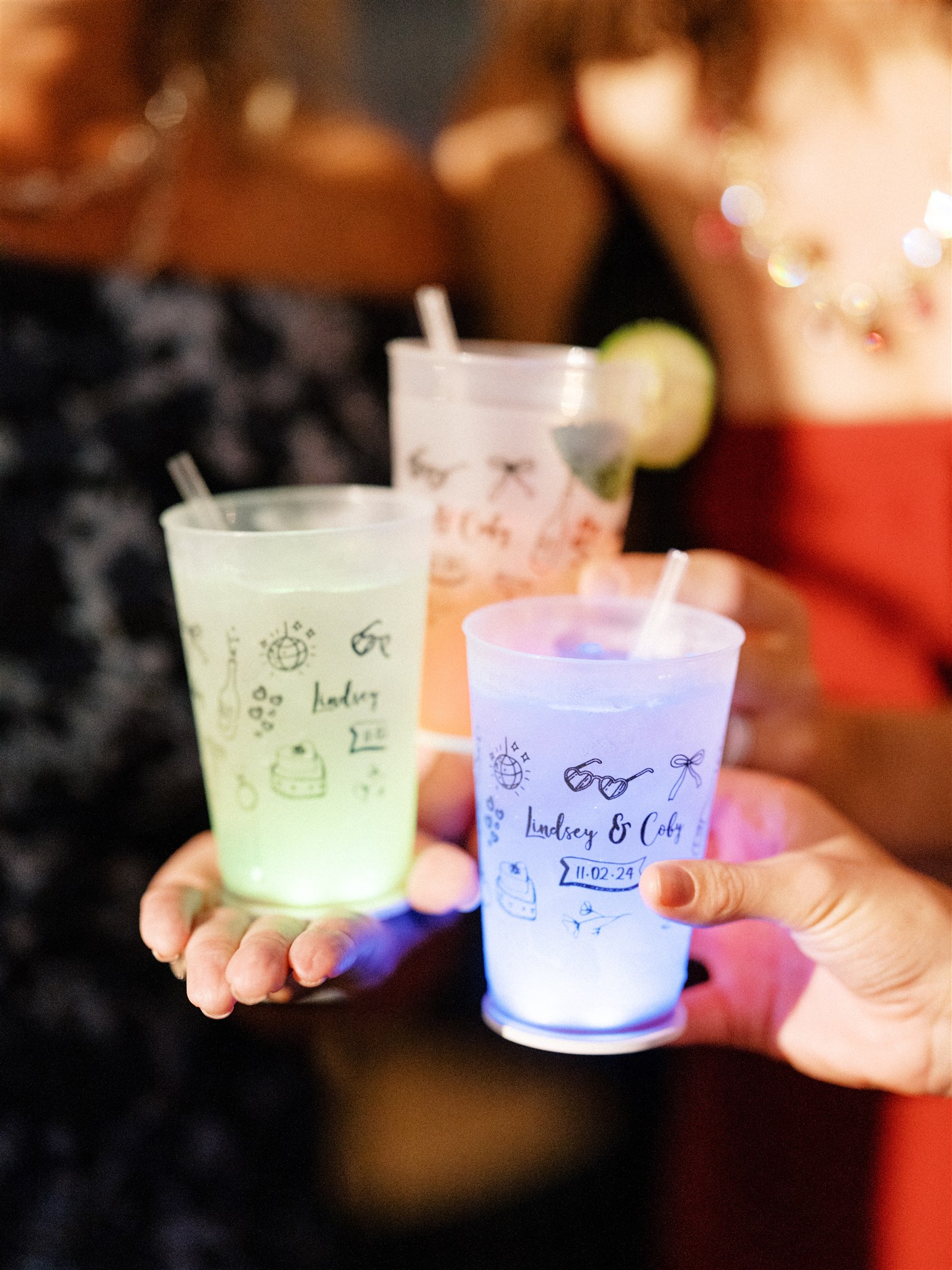 A close-up of three plastic frost flex cups with a custom design. An LED coaster stuck to the bottom of each cup lights them up with color.