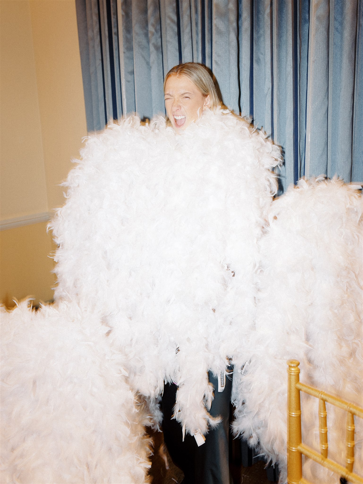 A Pop Parties wedding planner poses with a pile of white feather boas as she prepares to hand them out to late night wedding guests.