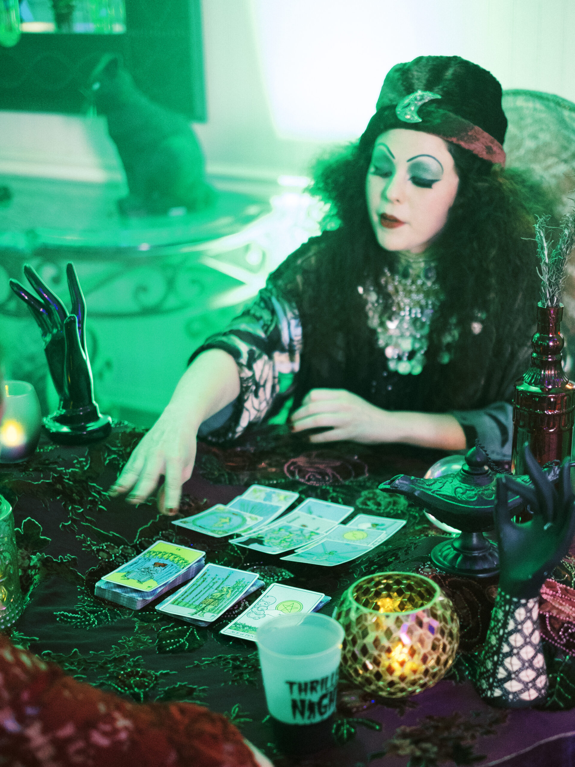 A tarot card reader in spooky Halloween garb dazzles guests at a themed party.