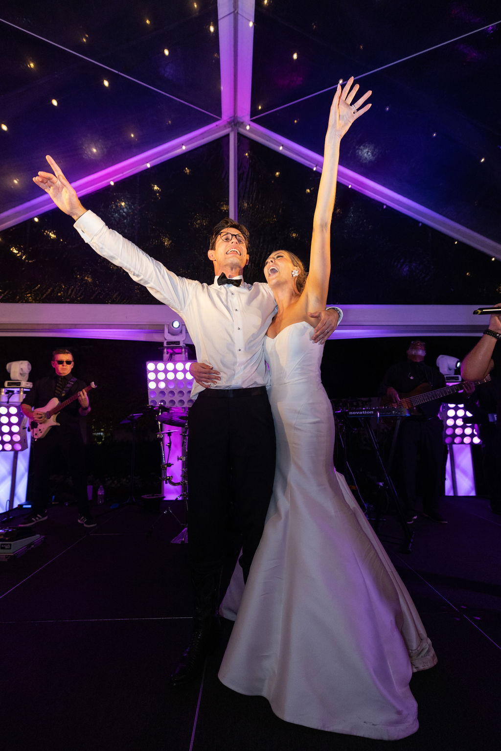A newlywed couple sways together on the dance floor, singing aloud in a candid moment.