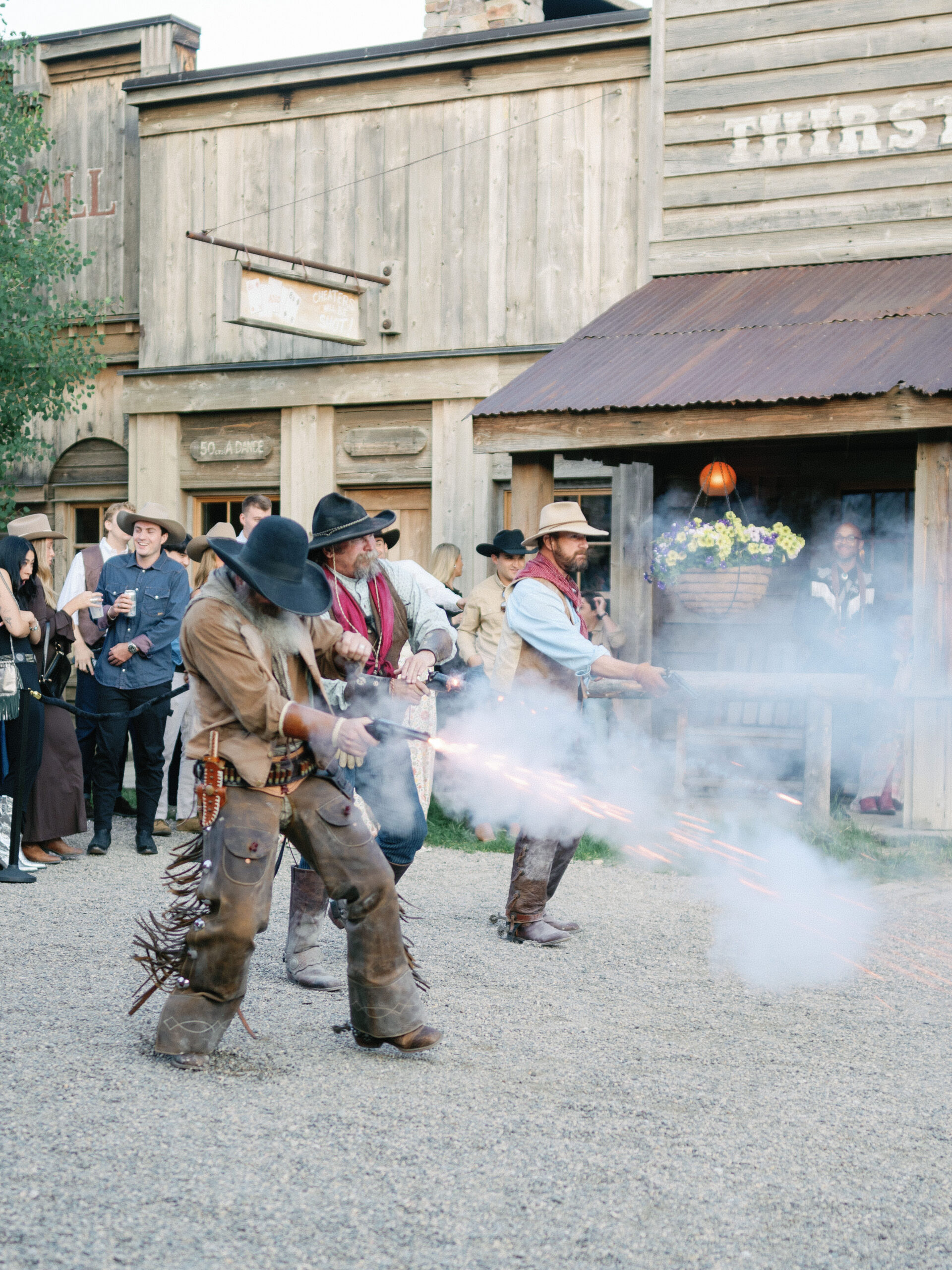 Three actors dressed like Old West cowboys participate in a simulated shootout as entertainment for a mountain welcome party.