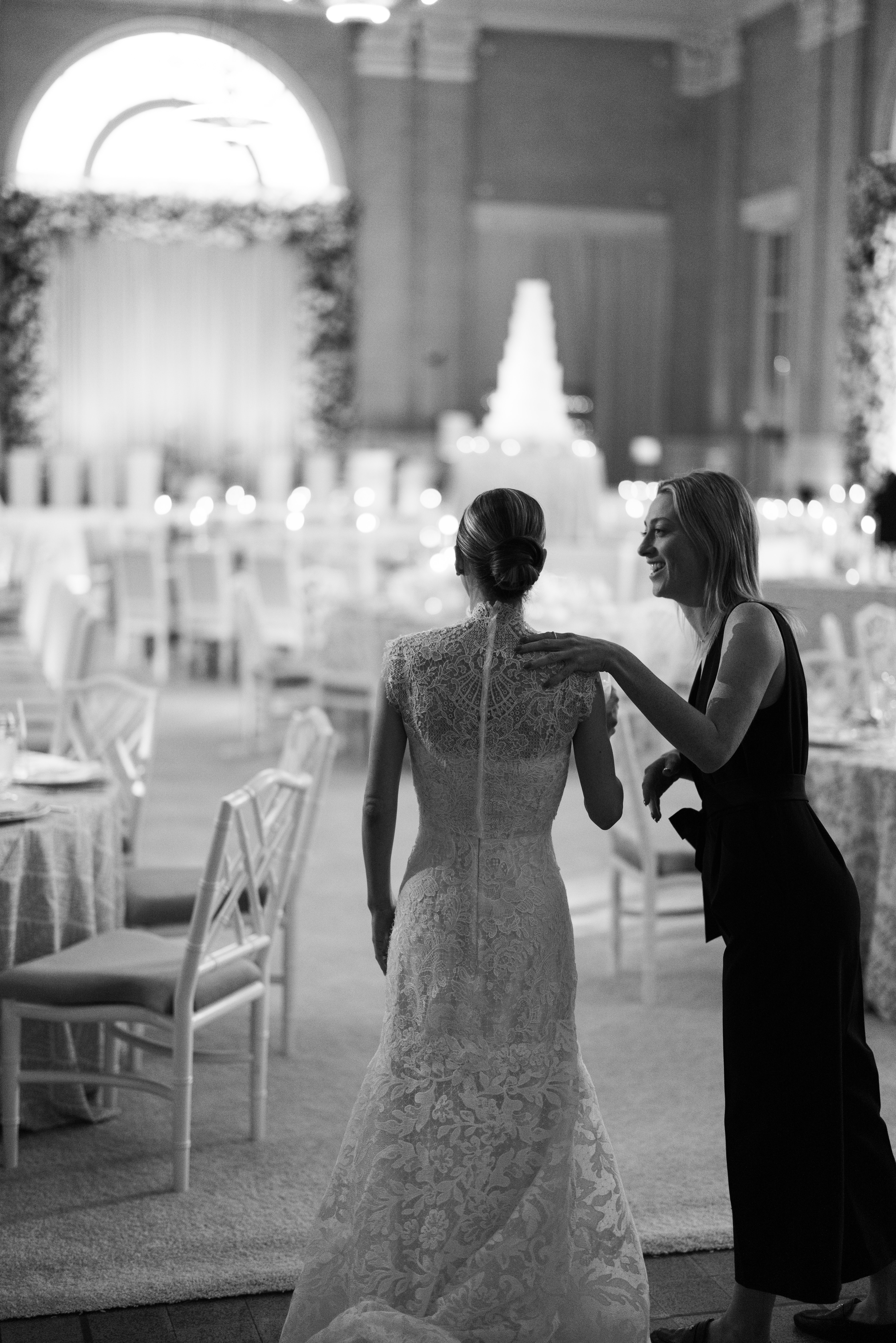 A wedding planner shows a happy bride her vision come to life in a grand ballroom.