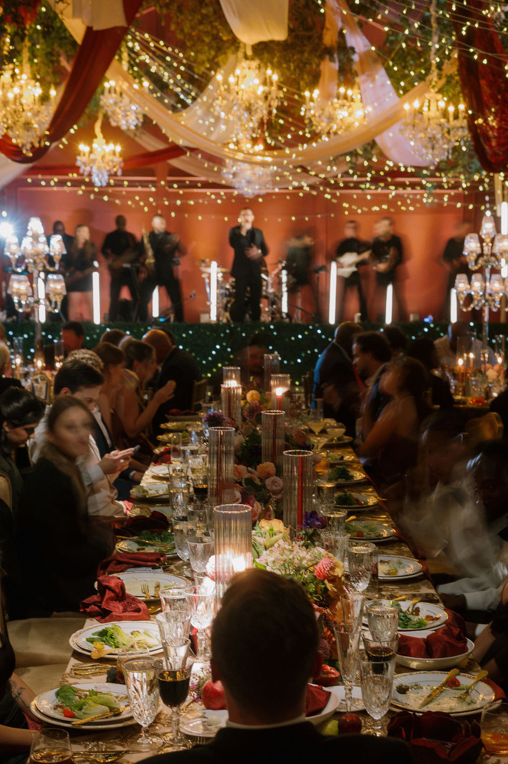 An artistic photograph of a wedding reception, the lights from the stage blending gently into the candid image.